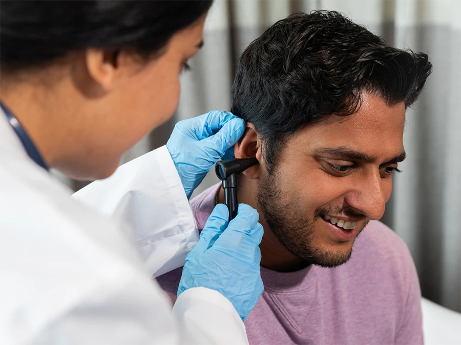 Doctor performing CDL physical exam in Gulfton using an otoscope on patient