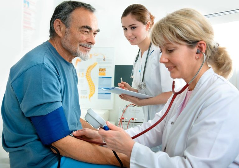 A doctor performing an affordable DOT physical in Houston, using a stethoscope and blood pressure monitor in a clinic.