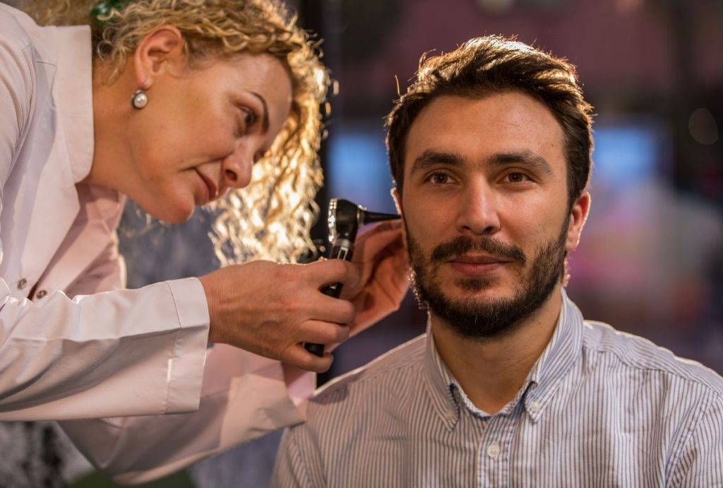 Doctor performs ear exam with otoscope as part of CDL Physical Houston certified medical evaluation process.
