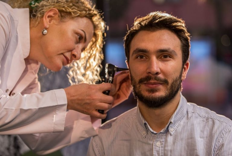 Doctor performs ear exam with otoscope as part of CDL Physical Houston certified medical evaluation process.