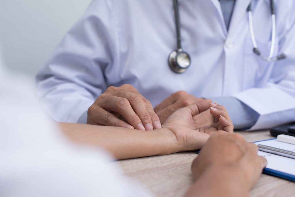 Close up of a healthcare provider checking a driver's pulse and vitals during a scheduled DOT physical Houston exam.