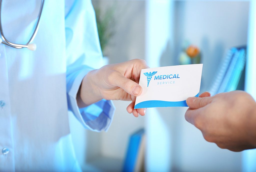 FMCSA Medical Examiner Houston doctor hands a professional medical service card to a commercial driver during examination.