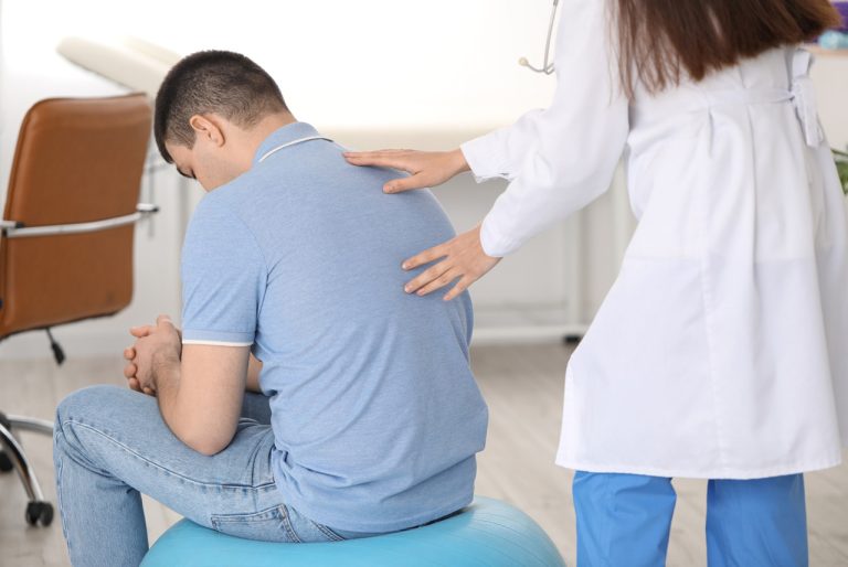 Certified medical examiner performing a back exam during a DOT Physical Open Saturday Houston for CDL holders.