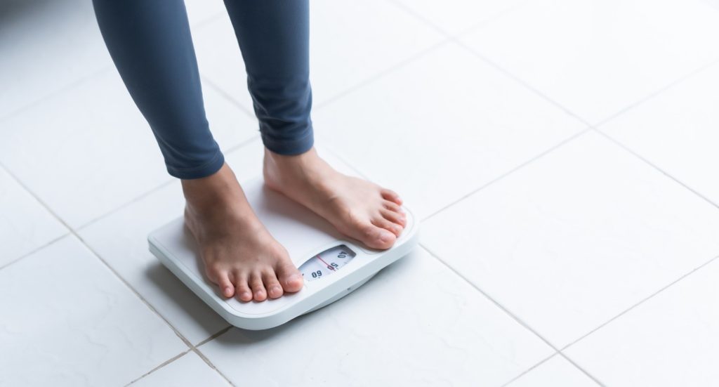 Person on scale for weight check during a Same Day DOT Physical Houston to meet FMCSA medical requirements.