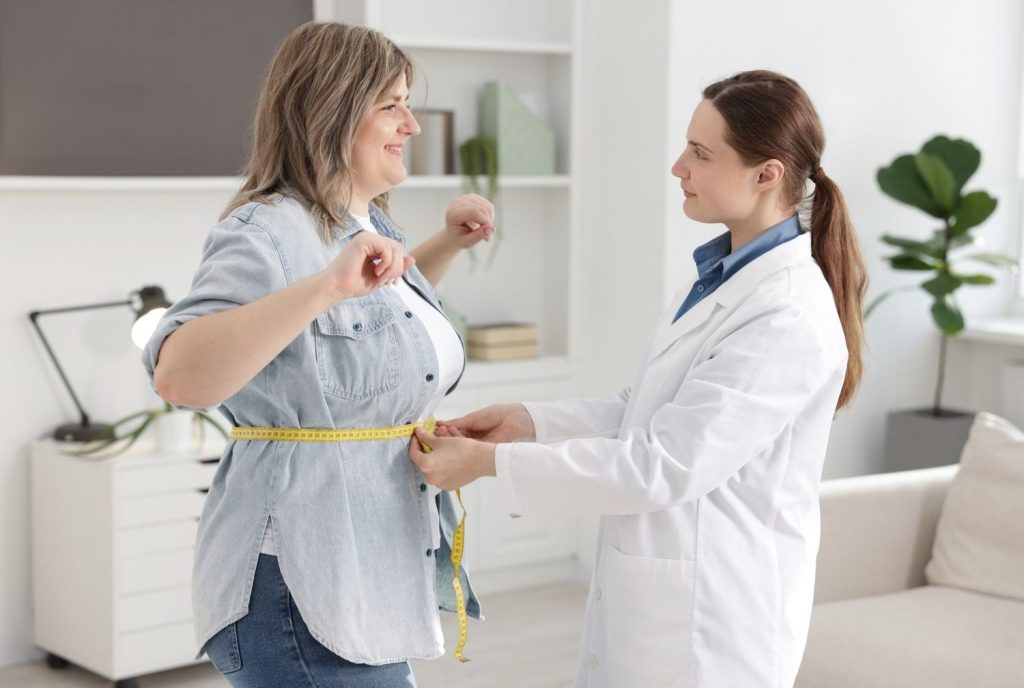 Medical examiner measuring waist circumference at a Same Day DOT Physical Houston clinic for driver health.