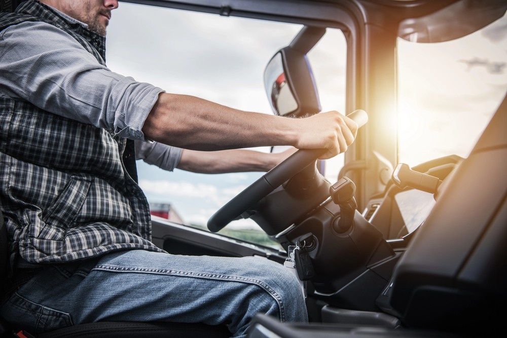 Truck driver focused at the wheel in a sunlit cab, safety prep before DOT Physical Houston TX exam