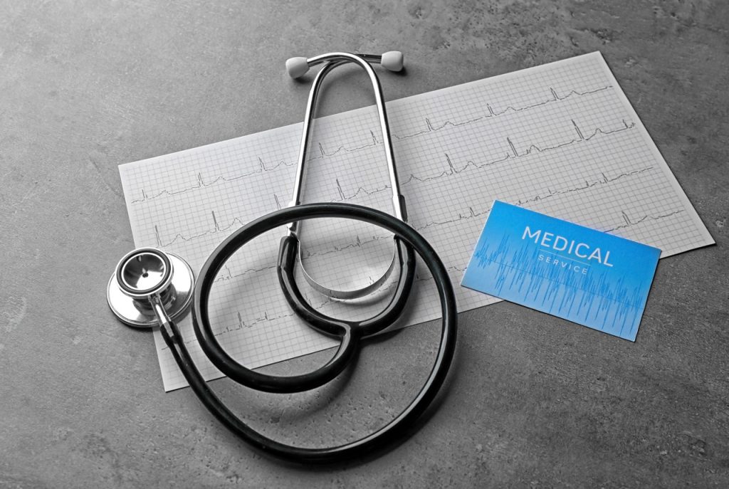 Medical tools for a cdl medical card houston exam including a stethoscope on an ECG heart rate monitor readout.