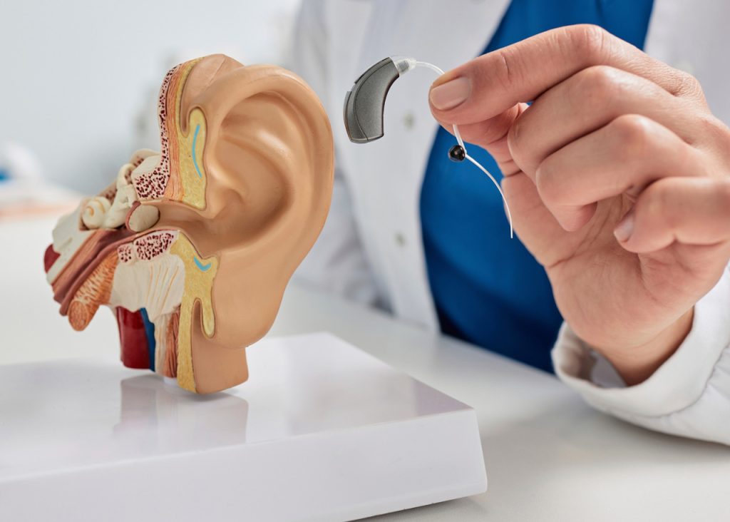 Audiologist showing a hearing aid for drivers seeking a CDL medical exam Houston to pass their safety evaluation.