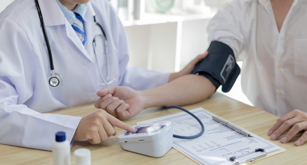 Digital blood pressure screening by a DOT certified medical examiner Houston during a commercial driver exam.