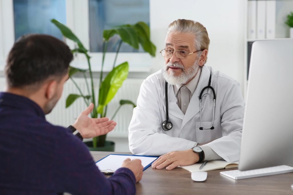 CDL driver discussing health requirements and certification during a visit to an FMCSA medical examiner in Houston.