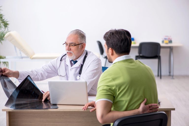 A senior FMCSA medical examiner Houston reviews back X-rays with a driver to ensure DOT physical exam compliance.
