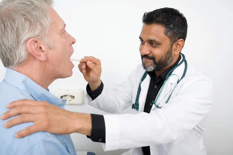 Close up of a doctor using a penlight and tongue depressor for a CDL medical card Houston DOT physical exam.