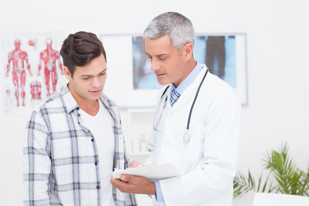 Fmcsa medical examiner houston clinic: a doctor in white coat reviews forms with a patient, with medical charts behind them.