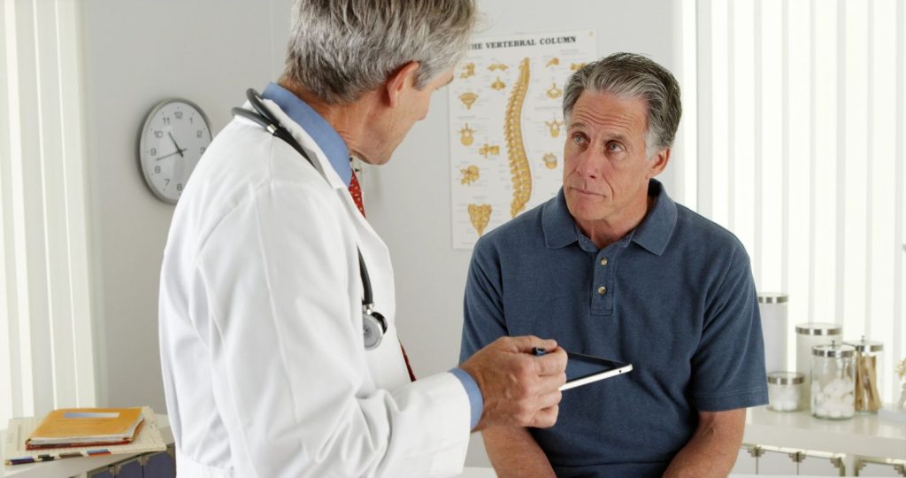A physician conducting a DOT medical exam Houston consultation for spine health and posture with a senior driver.