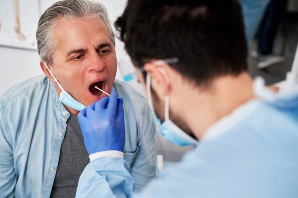 Certified DOT medical exam Houston drug and alcohol testing using a mouth swab on a commercial driver at a clinic.