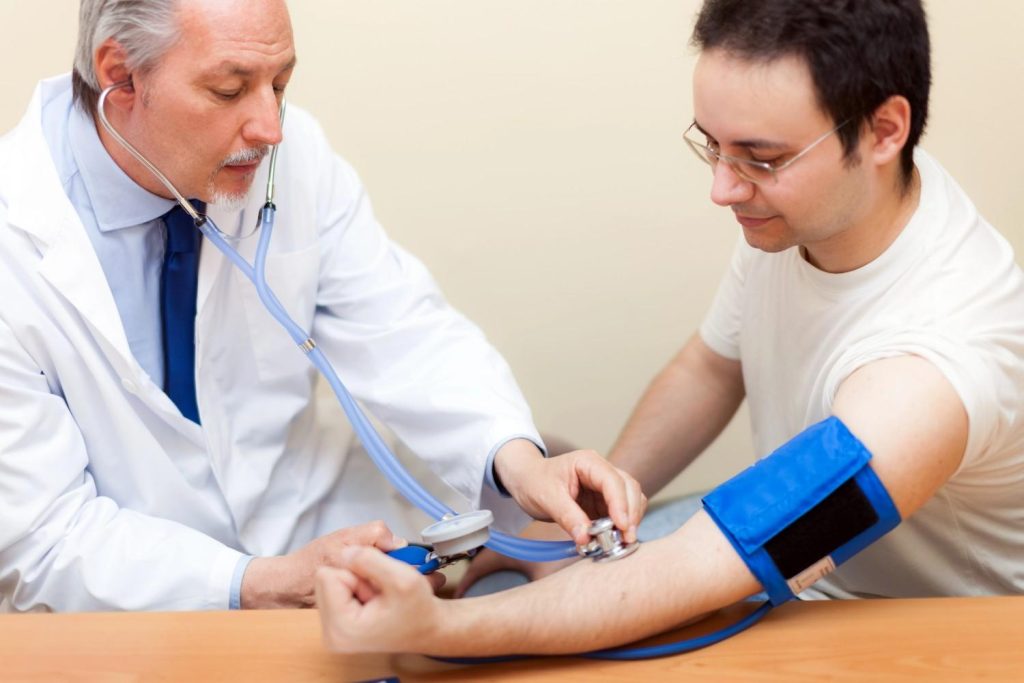 FMCSA medical examiner Houston checks a commercial driver's blood pressure during a standard DOT physical exam. 