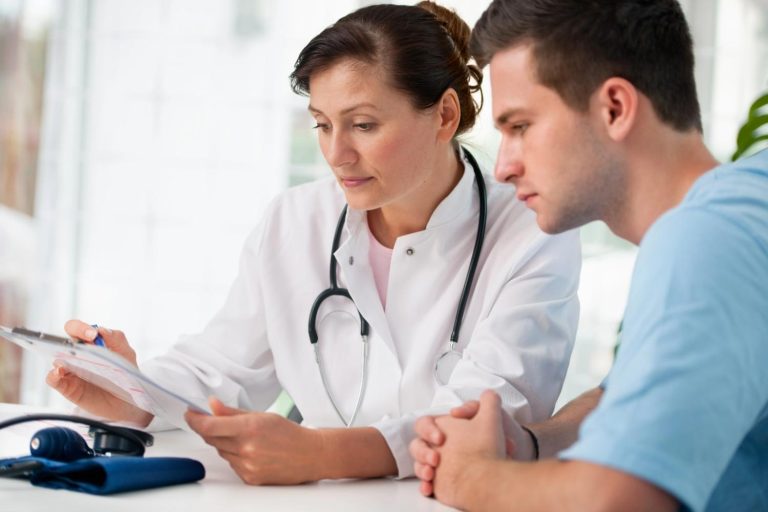 An FMCSA medical examiner Houston reviews medical history documents with a commercial truck driver client.