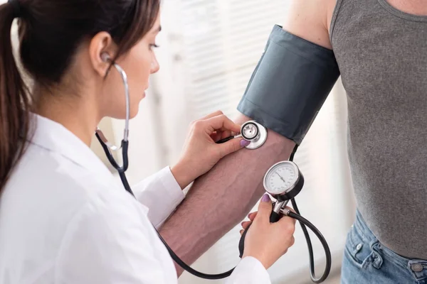 Female doctor checking a patient's blood pressure for a DOT medical exam.